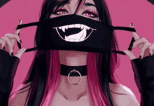 a girl with pink hair is wearing a black mask with a vampire mouth on it