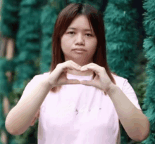 the woman is making a heart shape with her hands .