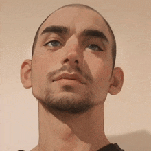 a close up of a man 's face with a shaved head and a beard .