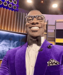 a man wearing a purple suit and bow tie smiles