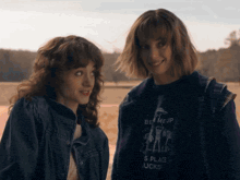 two women are standing next to each other and one of them is wearing a shirt that says be me up
