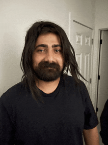 a man with long hair and a beard wears a black shirt