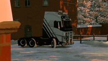 a volvo semi truck is parked in the snow in front of a building