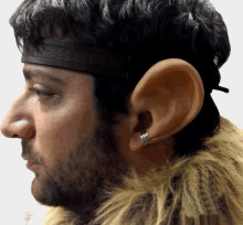 a man with a beard is wearing a headband and earrings .