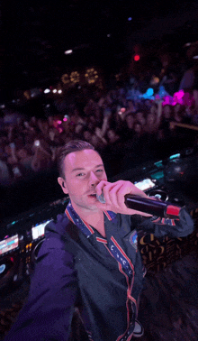 a man is singing into a microphone with a crowd behind him