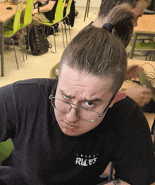 a man wearing glasses and a shirt that says rules