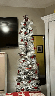 a tall white christmas tree with red cardinals