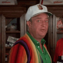 a man wearing a white hat and a rainbow sweater is making a funny face