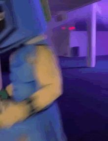 a blurry picture of a person standing in a dark room with purple lights .