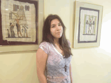 a woman stands in front of two framed pictures one of which says 00