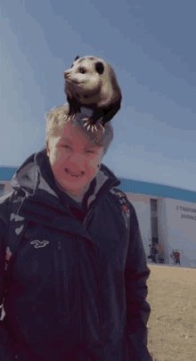 a person with an opossum on their head in front of a school