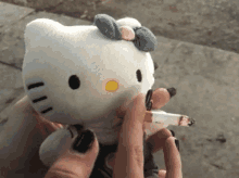 a person is holding a stuffed hello kitty while smoking a cigarette