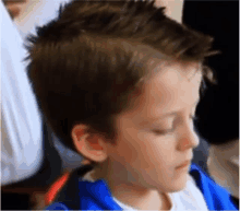 a young boy is getting his hair cut by a hairdresser in a blue jacket .