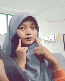 a woman wearing a hijab is giving a middle finger