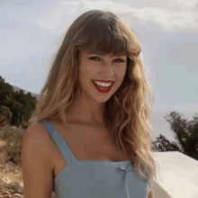 a woman with blonde hair and red lipstick is smiling for the camera