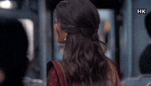a woman with her hair in a half up half down ponytail is looking over her shoulder .