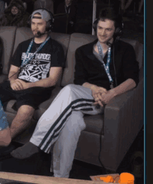 two men are sitting on a couch with one wearing a shirt that says enjoy thunder