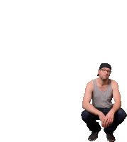 a man squatting down wearing a tank top and a hat