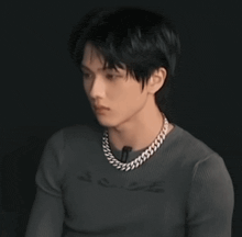 a young man wearing a chain around his neck and a black shirt
