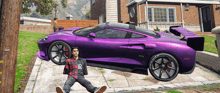 a man laying on the ground next to a purple car that says gpx on it