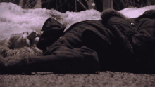 a woman laying on the ground wearing glasses and a black coat