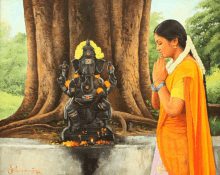 a woman prays in front of a statue of ganesha