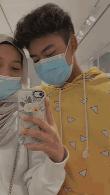 a man and a woman wearing face masks are taking a picture of themselves