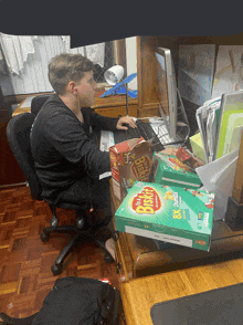 a boy sits at a desk with a box of biskuit