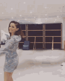 a woman is dancing in a room with a fire extinguisher on the wall