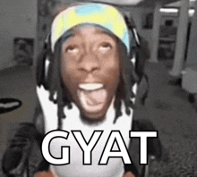 a man wearing headphones is making a funny face and the word gyat is above him