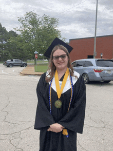 a woman in a graduation cap and gown with a medal around her neck stands in a parking lot