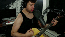 a man wearing headphones is playing a guitar in front of a rode microphone