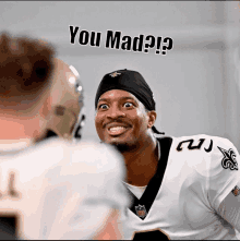 a man in a saints jersey is looking at another man with the words you mad below him