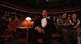 a man in a tuxedo is covering his nose with his hand in a crowd