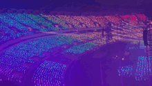 a crowd of people in a stadium with a rainbow of lights on the stands