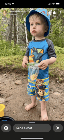 a little boy wearing a paw patrol shirt is holding a bag of food