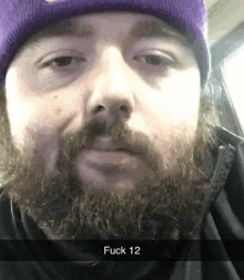 a man with a beard wearing a purple beanie says fuck 12 on the bottom