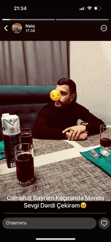 a man with a smiley face on his face sits at a table with drinks