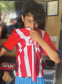 a young man wearing a red and white adidas shirt covering his face