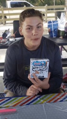 a young boy is holding a box of snack surprises