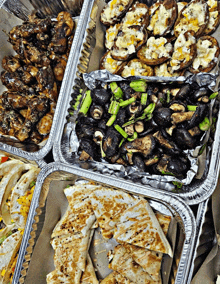 several trays of food including mushrooms quesadillas and asparagus