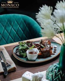 a plate of food from monaco sits on a table next to a vase of flowers