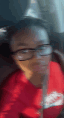 a blurry picture of a person wearing glasses and a red shirt