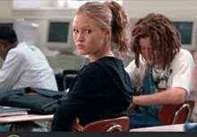 a girl with a ponytail is sitting in a classroom