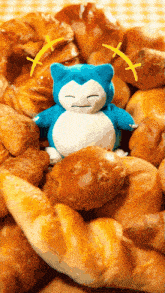 a stuffed animal is sitting on top of a pile of croissants