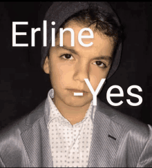 a young boy wearing a hat and a suit has the name erline written on his face