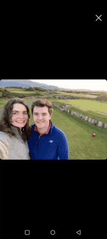 a man and a woman are posing for a selfie in front of a golf course .