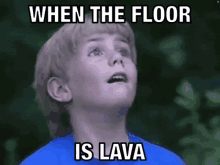 a young boy in a blue shirt is looking up at the sky with a caption that says `` when the floor is lava '' .