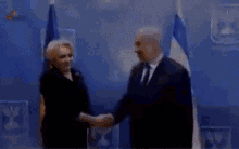 a man and woman shaking hands in front of a blue wall