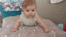 a baby is laying on a pillow with a floral pattern on it